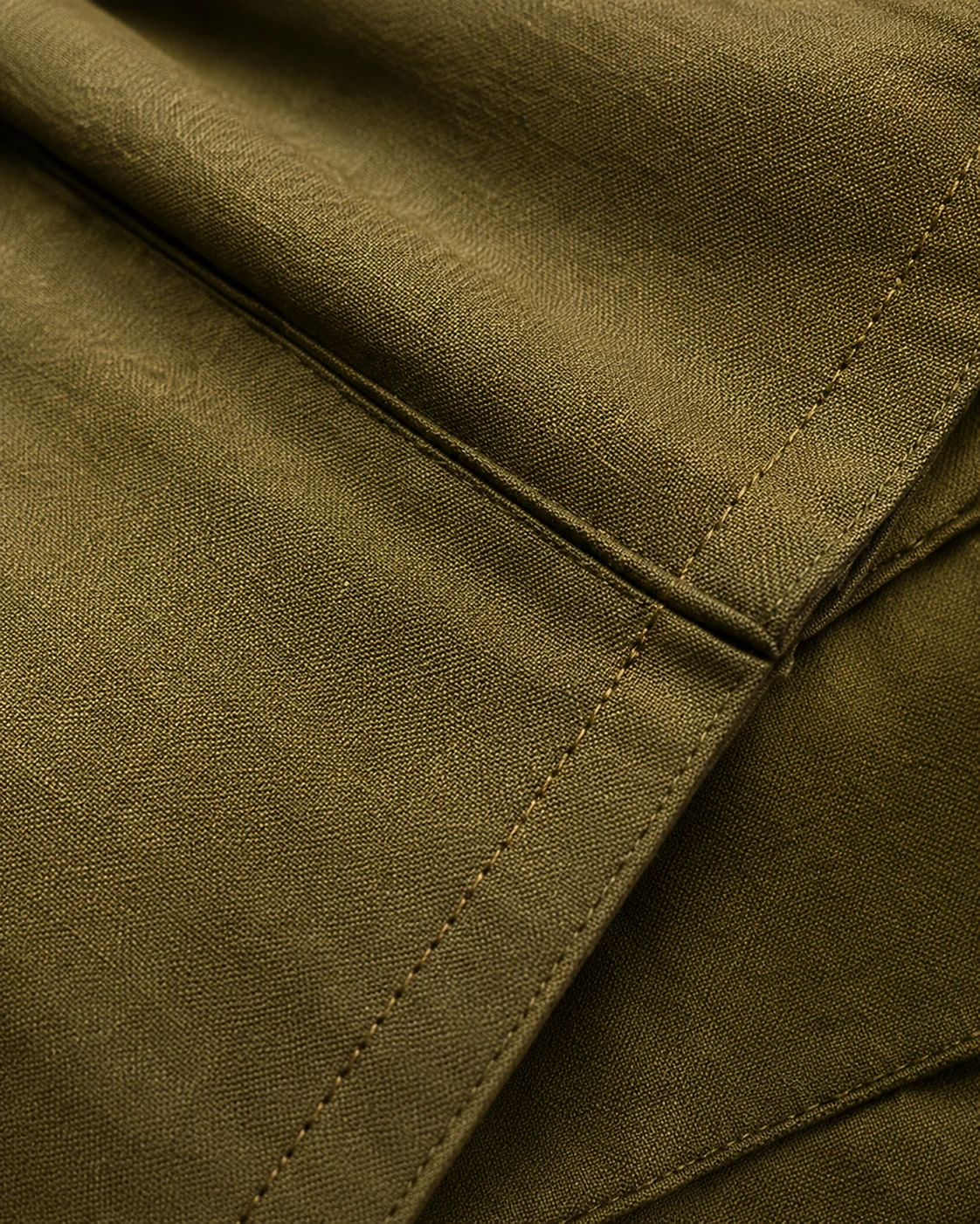 Close-up of olive linen with visible hand-finished stitching